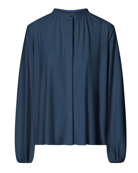 A navy-colored modest blouse with long sleeves, a high collar, and hidden buttons. The blouse has an elasticated cuff and is displayed in a relaxed, flowing manner.
